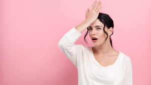 Woman holding her head in regret after making a mistake following a car accident.