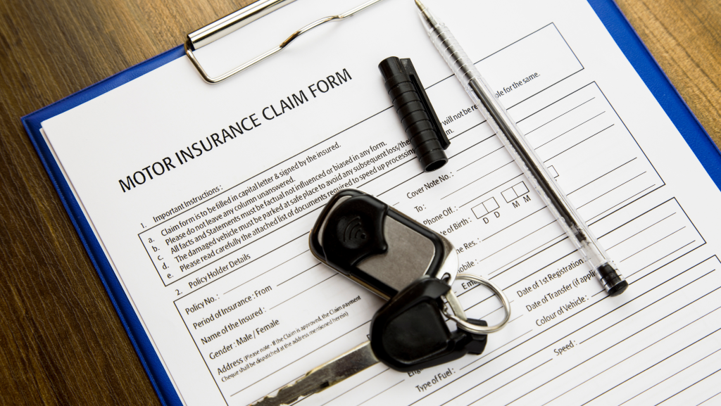 Auto insurance coverage claim form with car key and pen on clipboard.