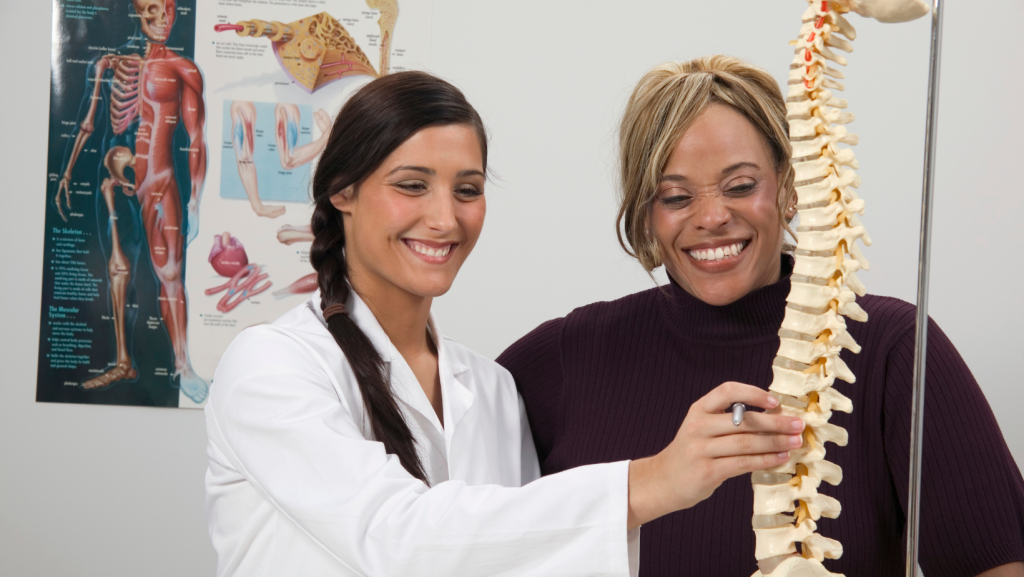 Top 5 Important Injuries Chiropractors Treat After an Accident for Relief Chiropractor showing spine model to patient while explaining injuries chiropractors treat